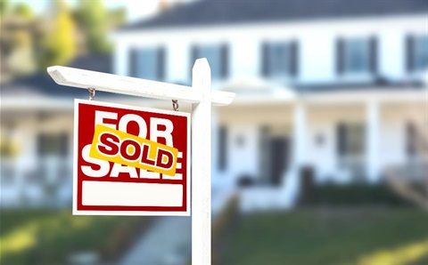 A sold sign in the foreground of a house.