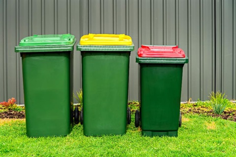 Three bins sit against a fence.