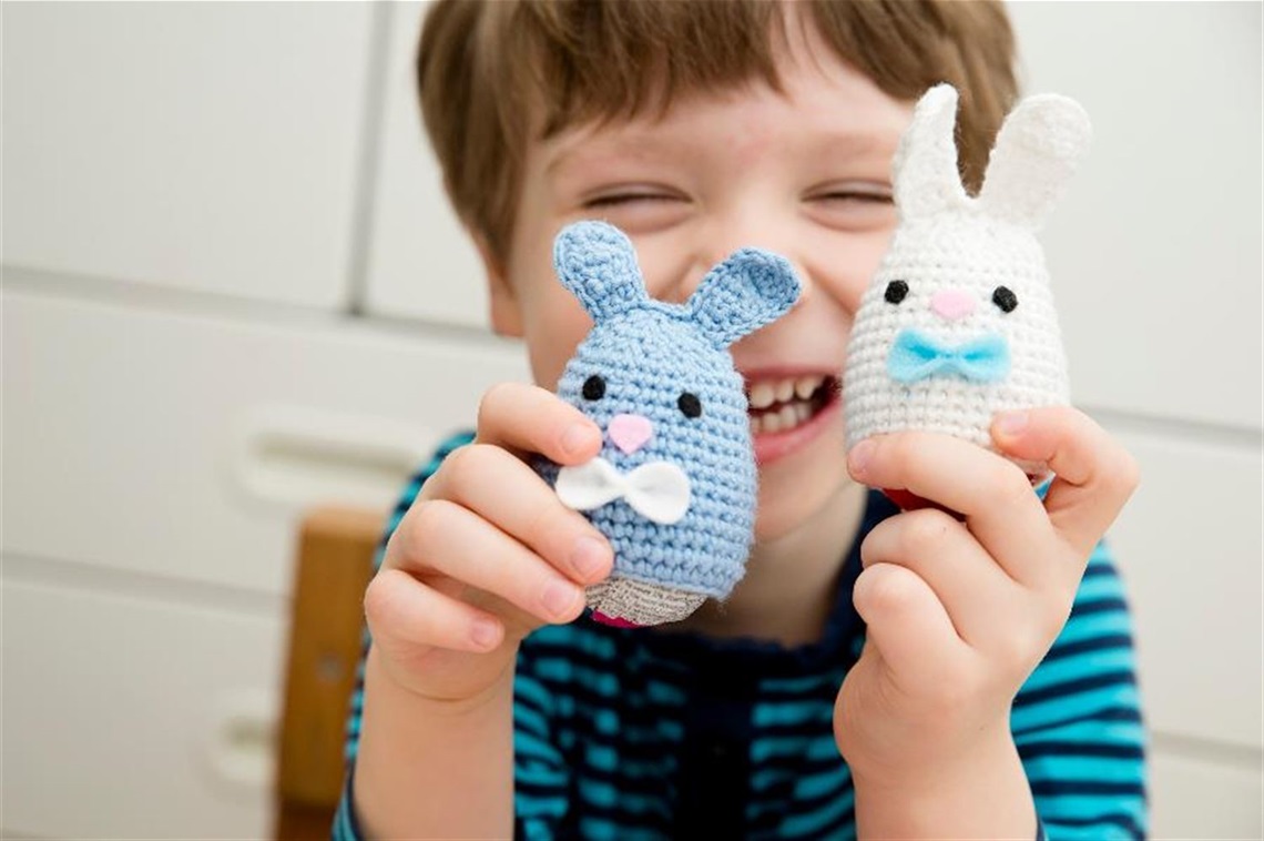 a little boy holding crochet bunnies