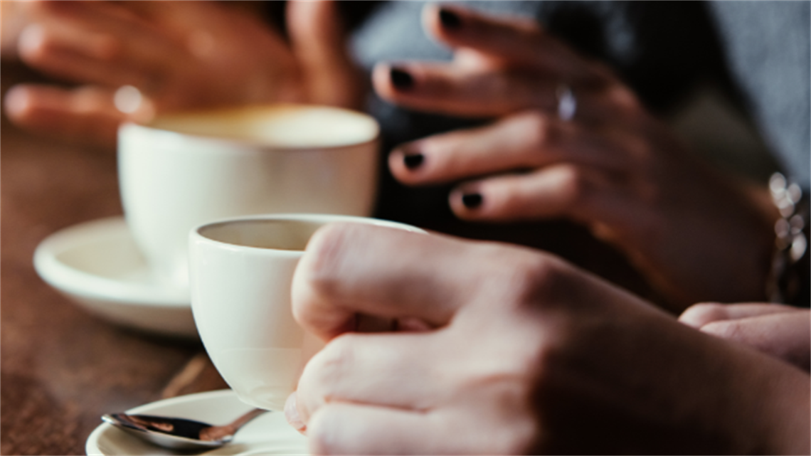 Two people having a conversation over coffee.