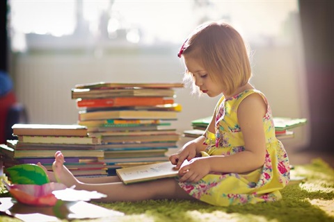 a child sits with a pile of books